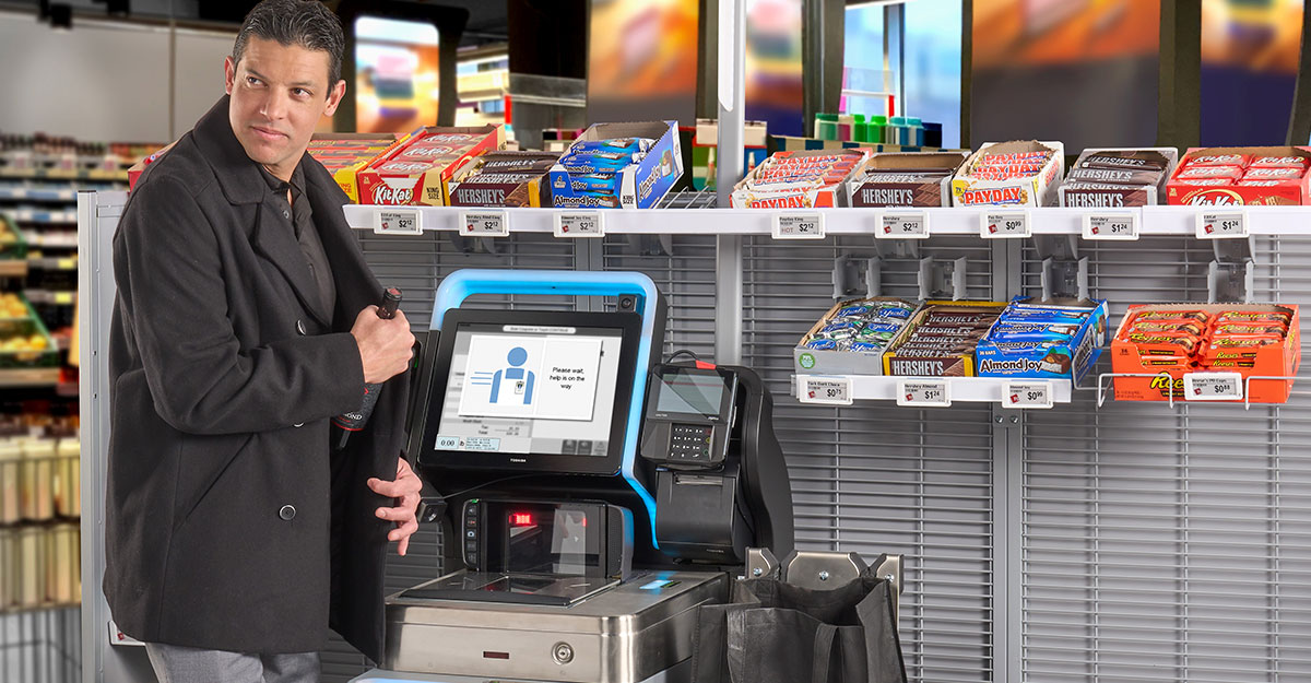 Man putting wine in his coat at a Toshiba System 7 self checkout machine Man putting wine in his coat at a Toshiba System 7 self checkout machine