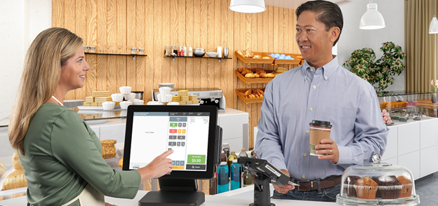 Woman using a point of sale system to check out a man buying coffee Woman using a point of sale system to check out a man buying coffee