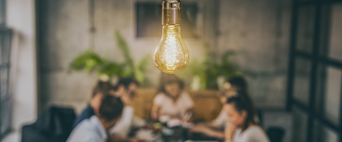 People at a table with a light bulb hanging in front of them People at a table with a light bulb hanging in front of them